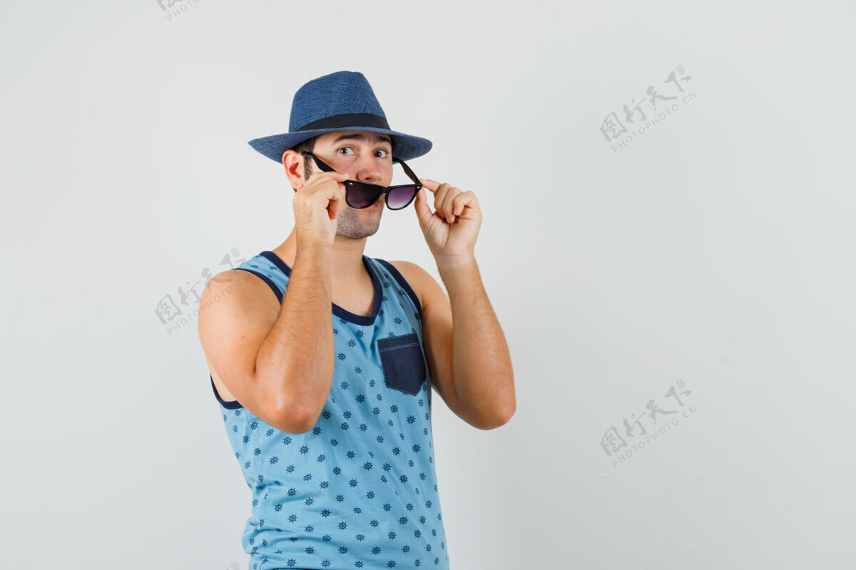 自信年轻人摘下眼镜 戴着蓝色的单打 戴着帽子 神情专注前视图脸男性前面