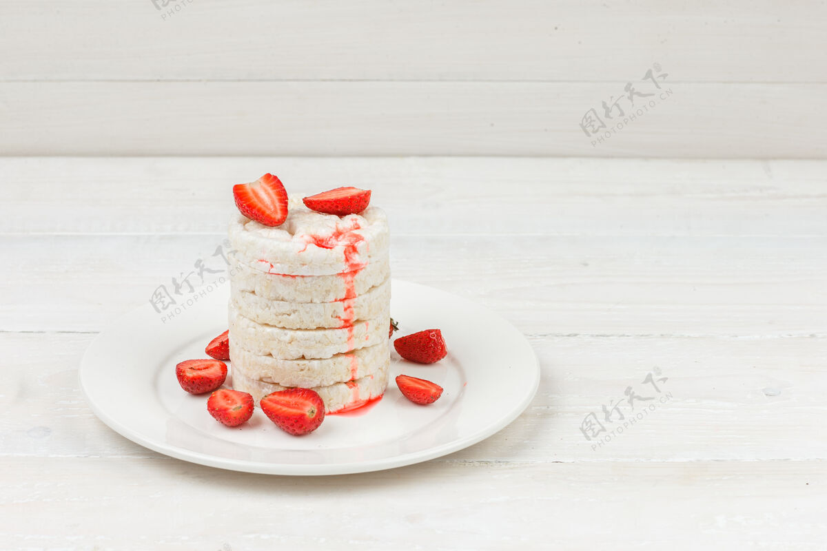 开胃菜高角度观看白色的米糕在盘子里 草莓放在白色的木板上茶新鲜蒸汽