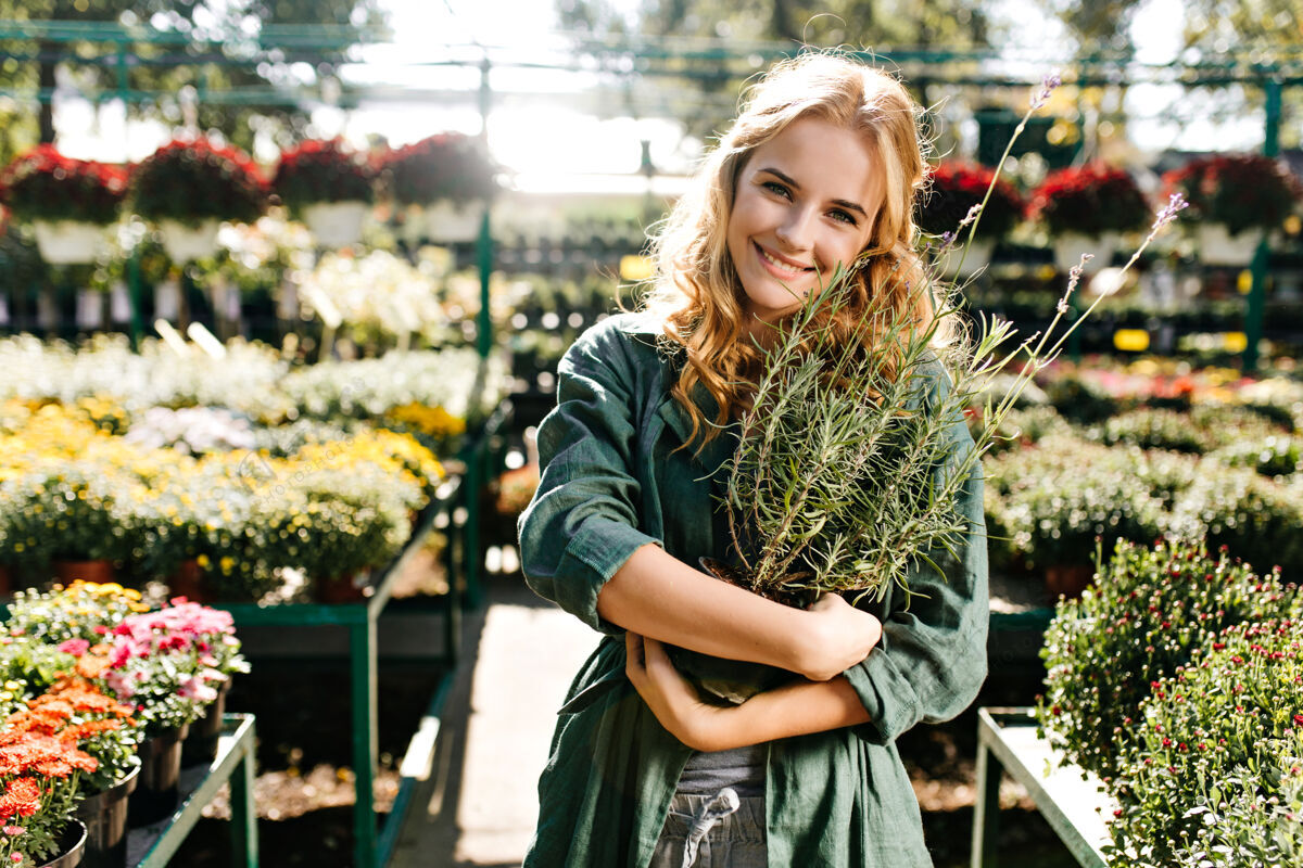 可爱一位金发碧眼 笑容温柔的年轻女子 身着绿色长袍 系着腰带 正在温室里工作年轻肖像花