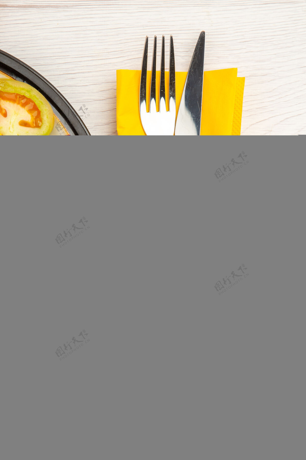 视图上半部分查看切碎的蔬菜和水果在黑色的盘子上叉子和刀在黄色的餐巾上在白色的桌子上容器砍顶部