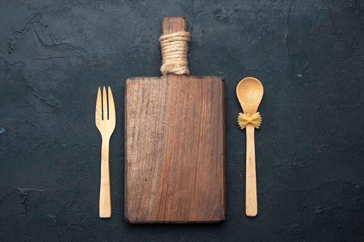 勺子顶视图砧板木勺和叉子在黑暗的表面梳子顶部