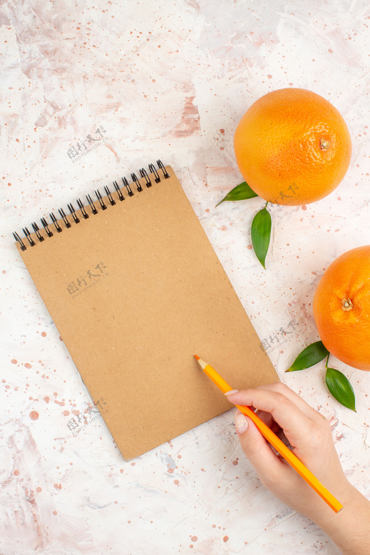 柑橘顶视图新鲜的橘子一个记事本橘子铅笔在女性手上明亮的表面自由的地方鲜橙脐橙位置