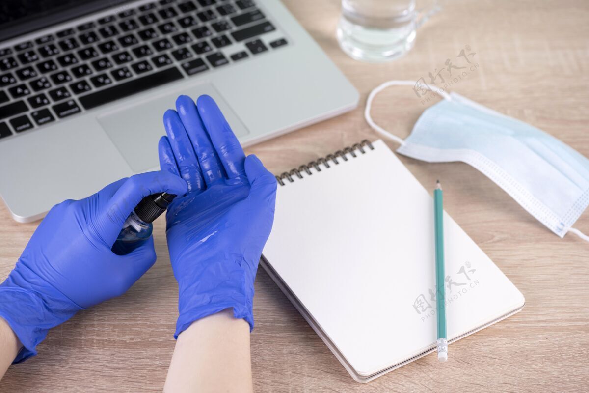 疾病高角度的手与手术手套使用洗手液旁边的办公桌医用面罩新常态Covid19
