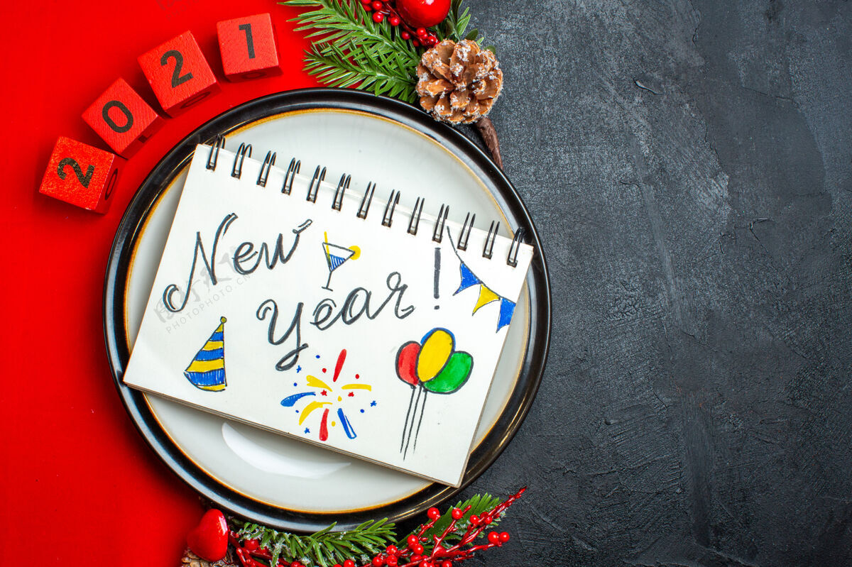 地球仪新年背景与笔记本新年图纸上的一个餐盘装饰配件杉木枝和数字在一个黑色的桌子上红色餐巾笔记本容器绘图
