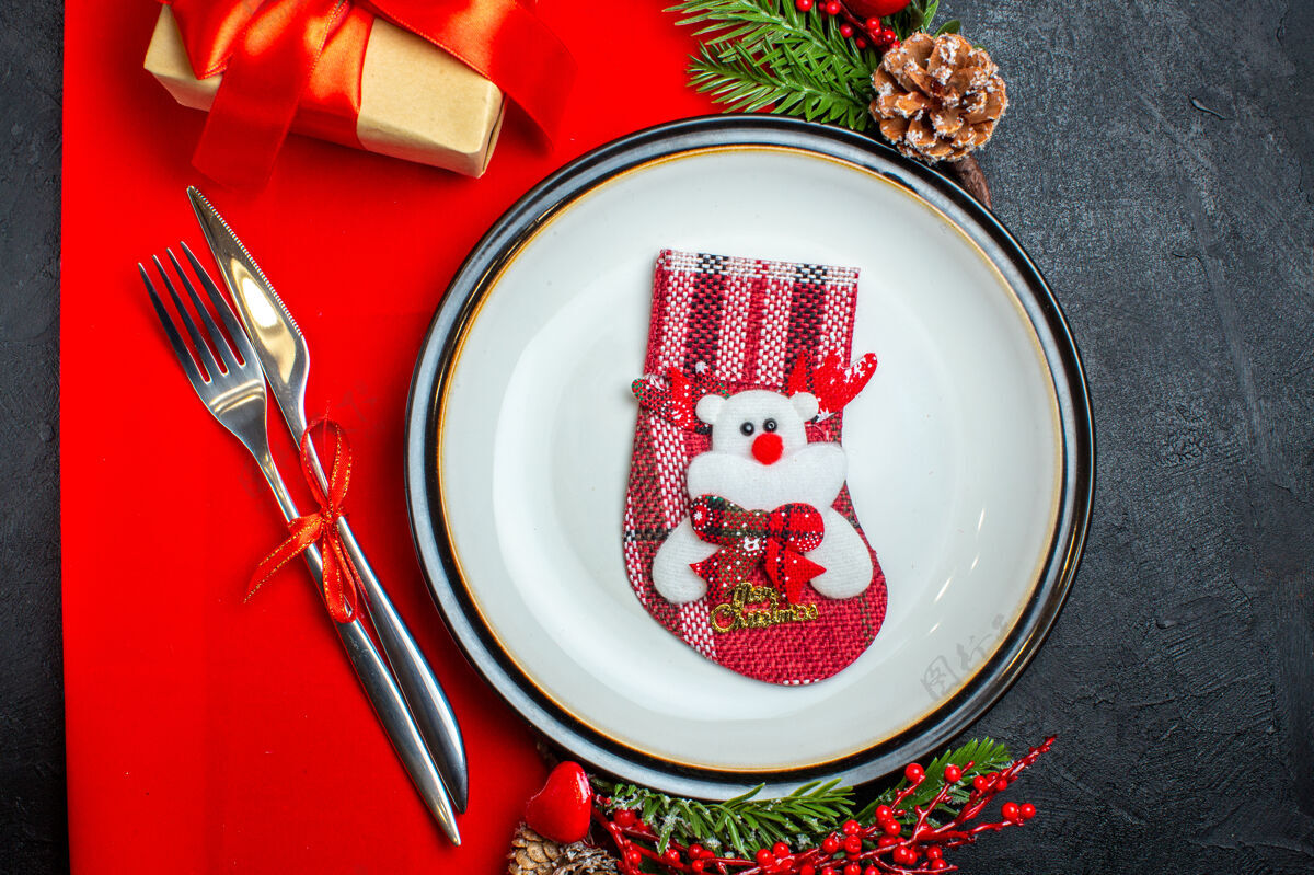 盘子横观新年背景 用袜子放在餐盘上餐具套装装饰配件杉木树枝旁边 一张红色餐巾上的礼物冷杉袜子餐厅