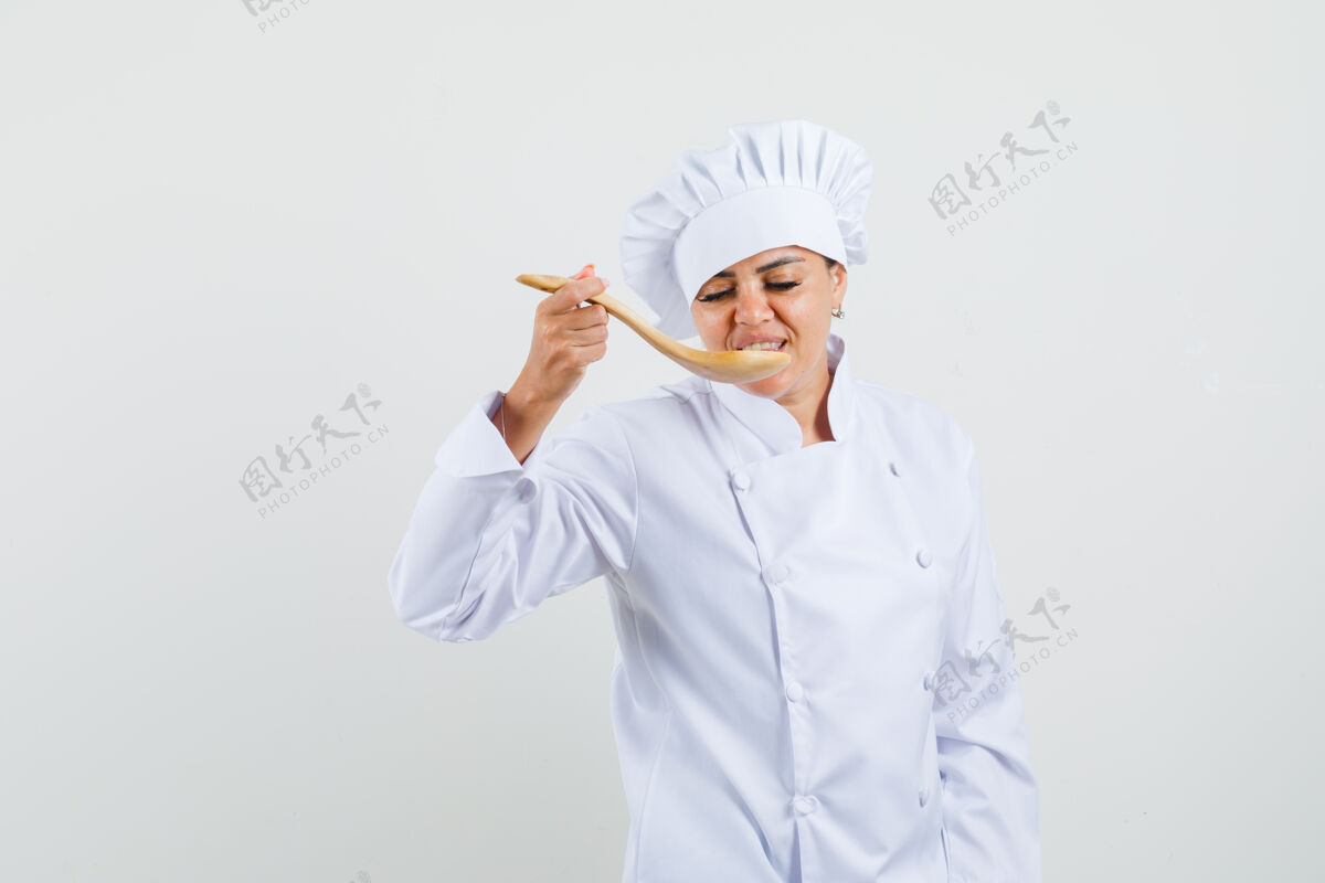 烹饪穿着白色制服的女厨师用木勺品尝美食服务举行新鲜