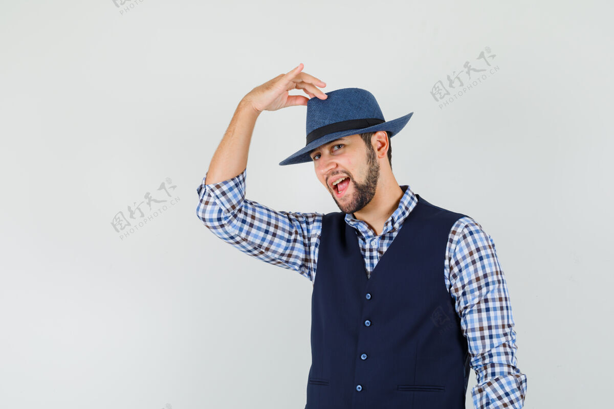 休闲年轻人穿着衬衫 背心 手指放在帽子上 看起来很自信 正面照胡须帅气聪明