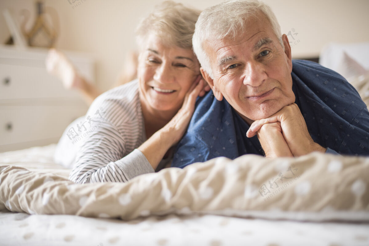躺着快乐的老年夫妇躺在床上活力休息卧室