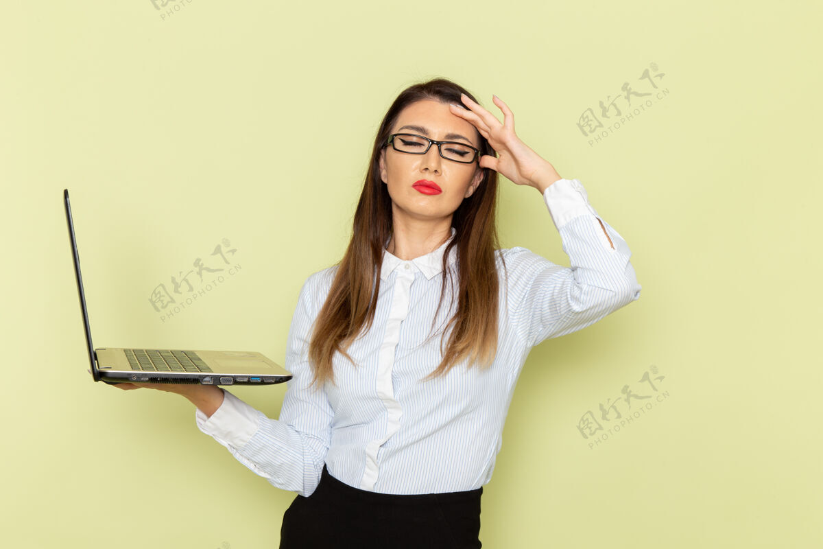 笔记本电脑穿着白衬衫和黑裙子的女上班族在绿墙上拿着笔记本电脑的正视图衬衫办公室快乐