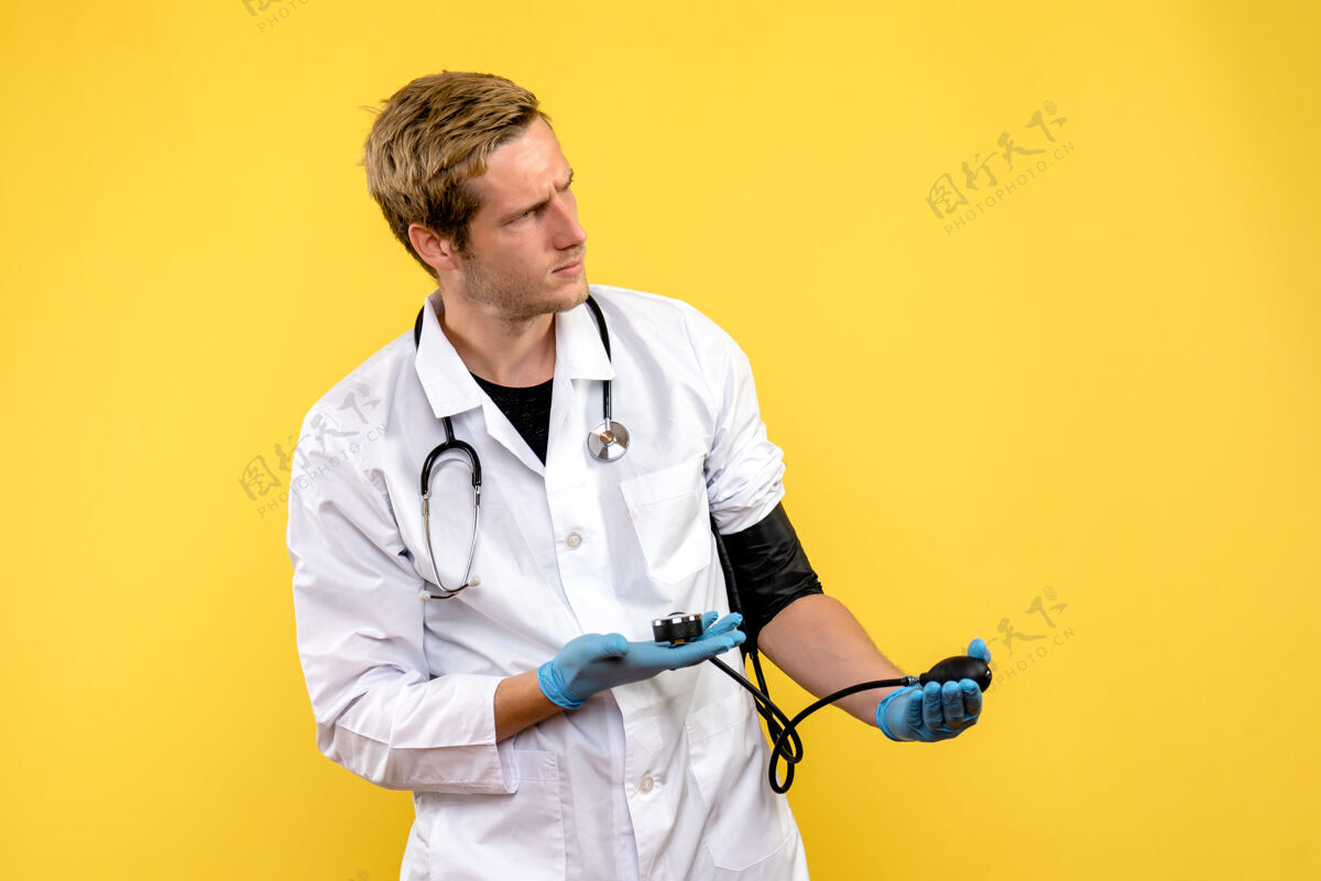 正面前视图男性医生测量他的压力对黄色背景病毒的健康医生比赛球员医学