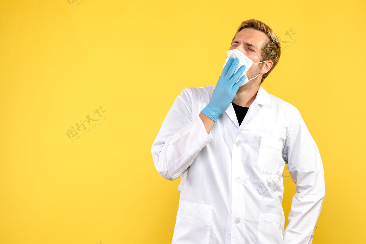 面具正面图黄色背景上戴着口罩打呵欠的男医生-医疗卫生大流行医疗专业实验室