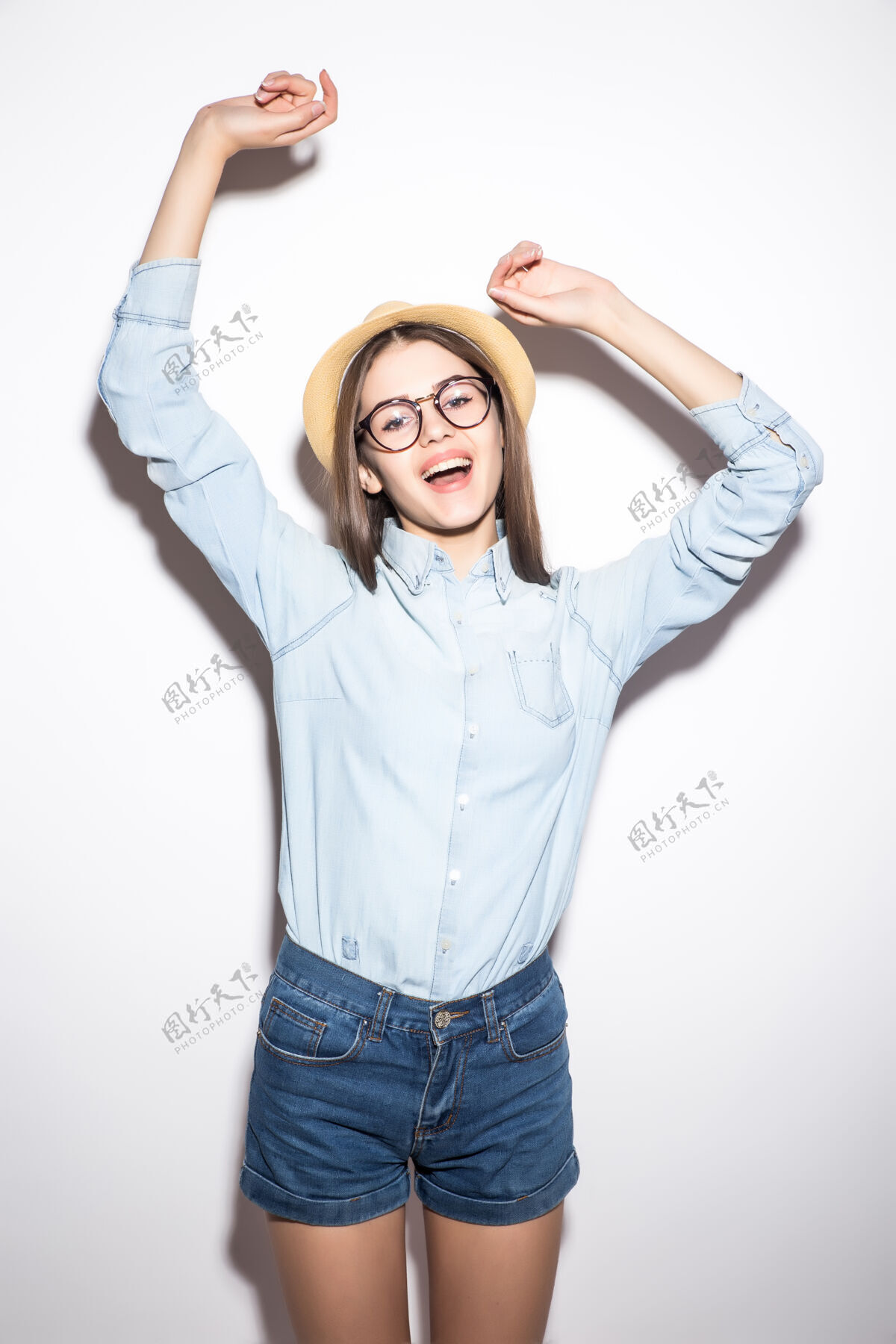 成人戴着草帽 穿着玫瑰短衫和蓝色短裤的快乐女孩积极年轻女人