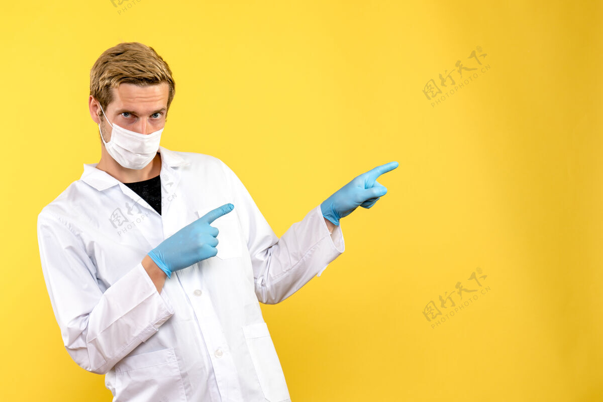 男性医生正面图黄色背景上戴着无菌口罩的男医生-大流行健康医生冠状病毒视图实验室外套