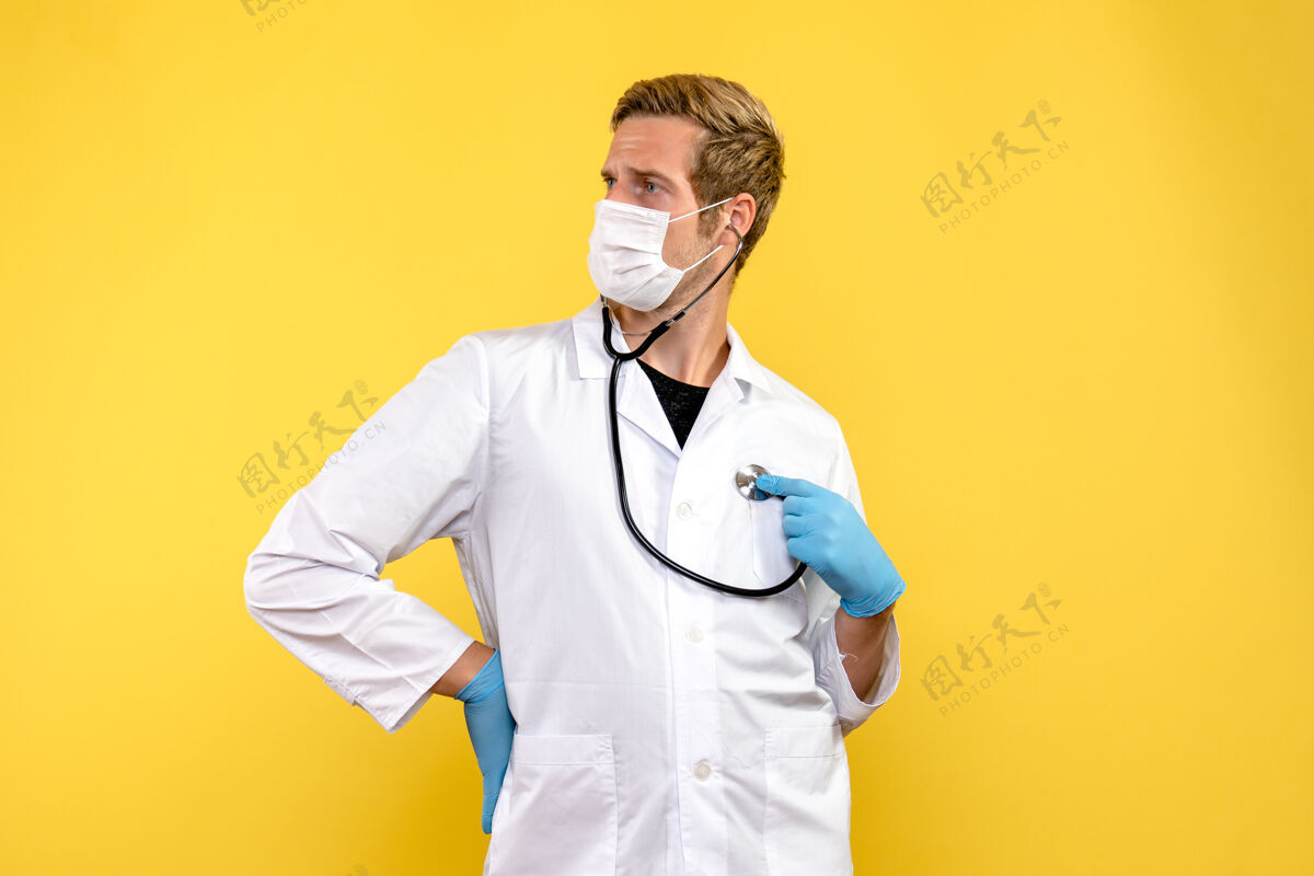 外套正面图男性医生戴着口罩 背景是黄色的病毒健康大流行病毒大流行专业人员服装