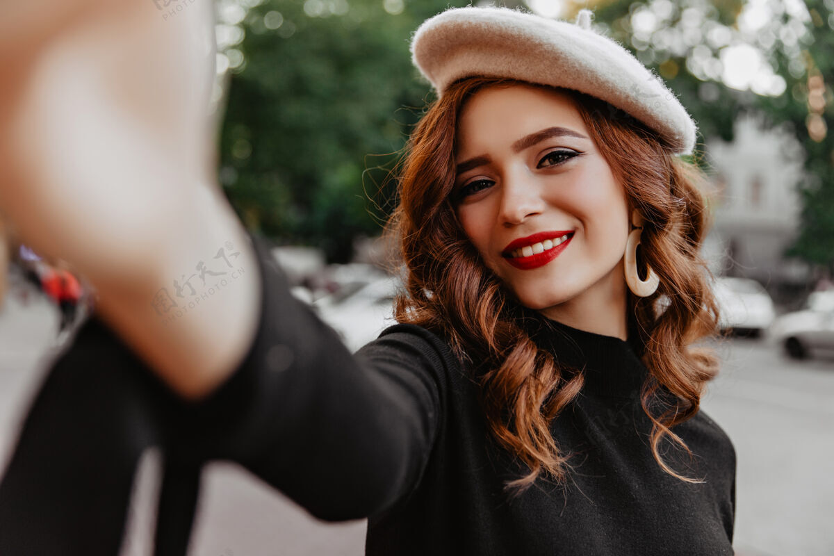 微笑11月的一天 一个长着姜黄色头发的漂亮法国女孩在街上摆姿势优雅的红唇白种女人在街上自拍的户外镜头季节享受自拍