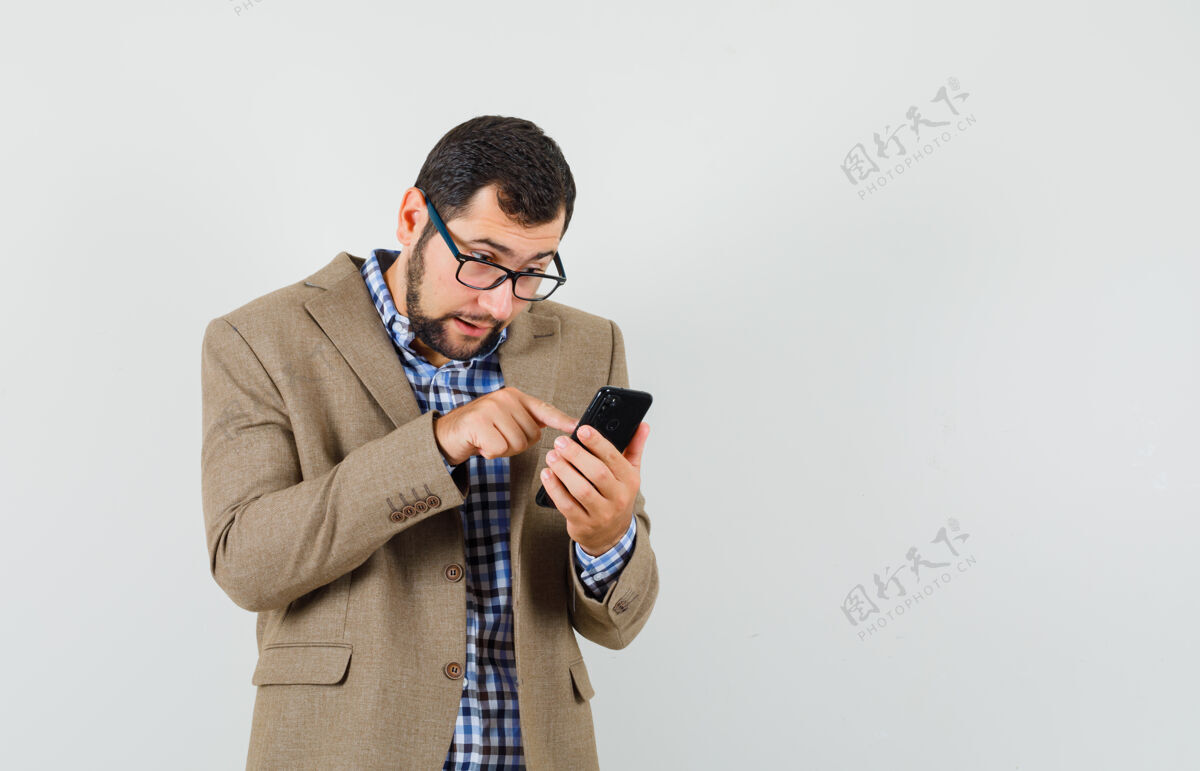 胡茬年轻人用手机在衬衫 夹克和看起来很忙胡须自信现代