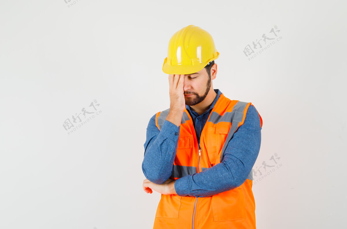 站年轻的建筑工人站在思考的姿势在衬衫 背心 头盔和看起来很累 前视图工作安全帽工厂