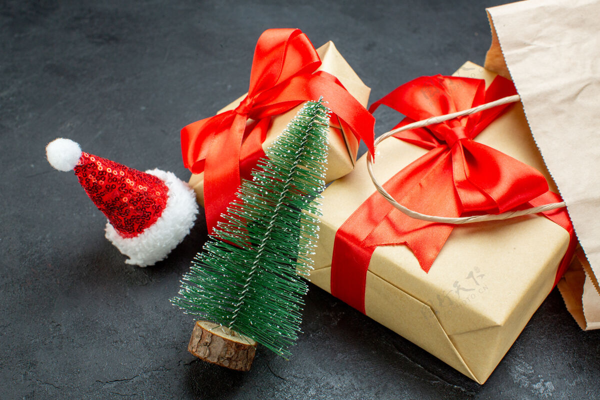 蝴蝶结前视图美丽的礼物与红丝带和圣诞树圣诞老人帽子在一个黑暗的桌子上风车圣诞节帽子