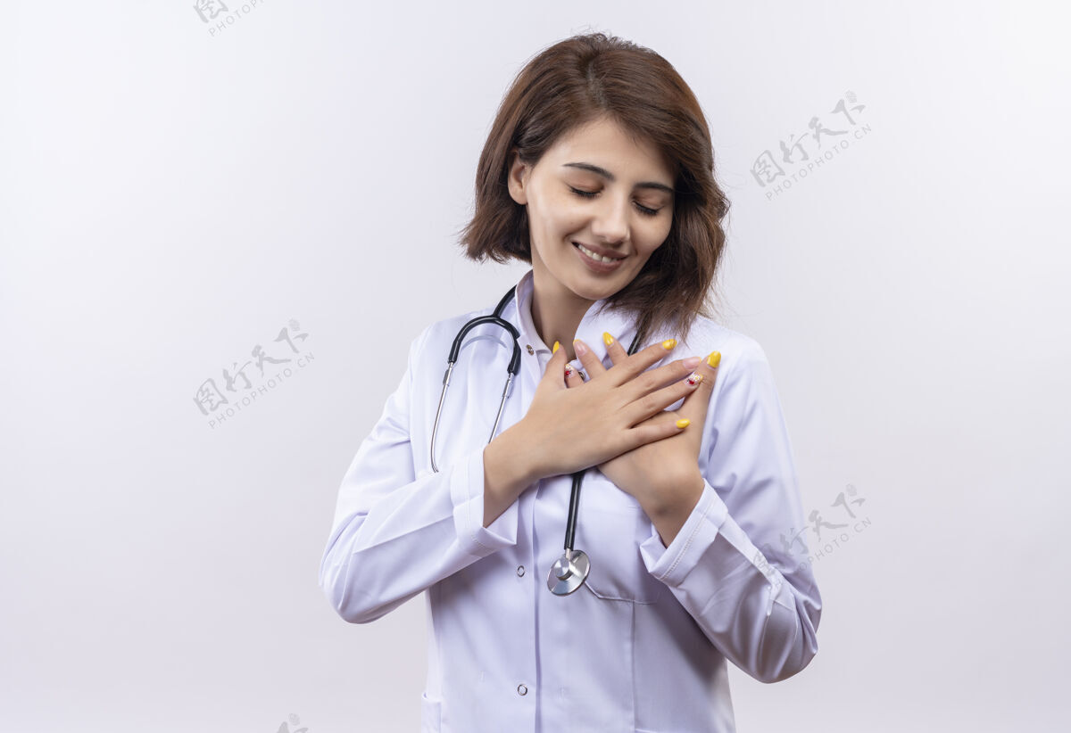 外套身穿白大褂的年轻女医生 手持听诊器 双臂交叉放在胸前 感受积极的情绪情绪胸部医生