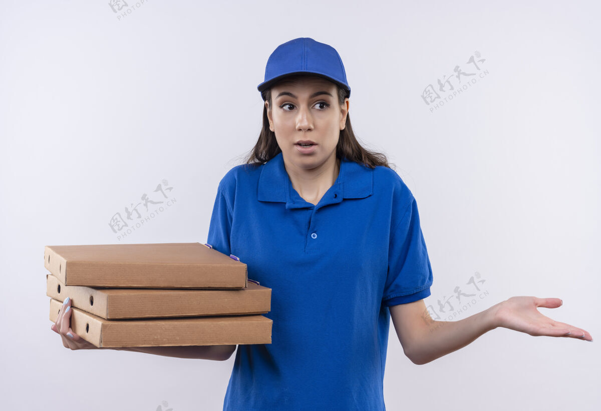 年轻年轻的送货员身穿蓝色制服 头戴鸭舌帽 手里拿着一叠披萨盒 神情茫然 困惑地耸耸肩帽子困惑肩膀