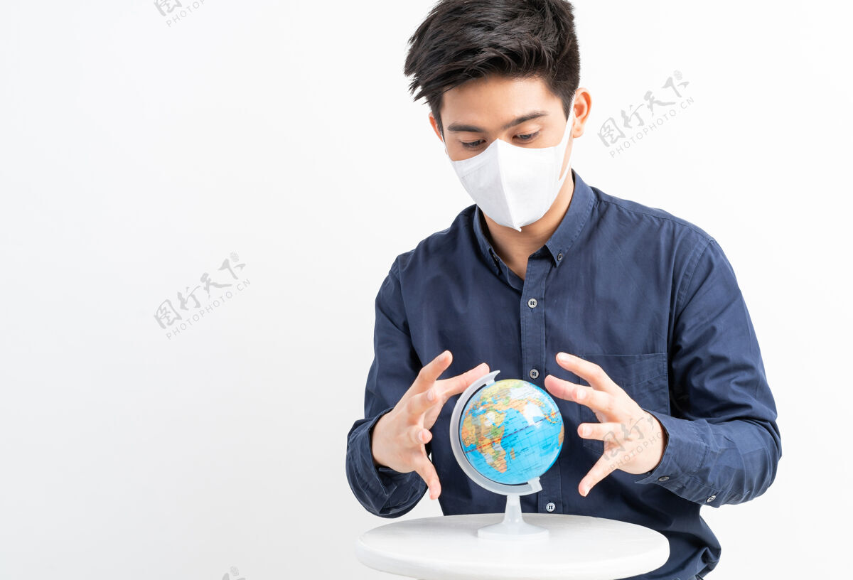 病毒戴着面具的亚洲人手里拿着世界地图地球悲伤紧张