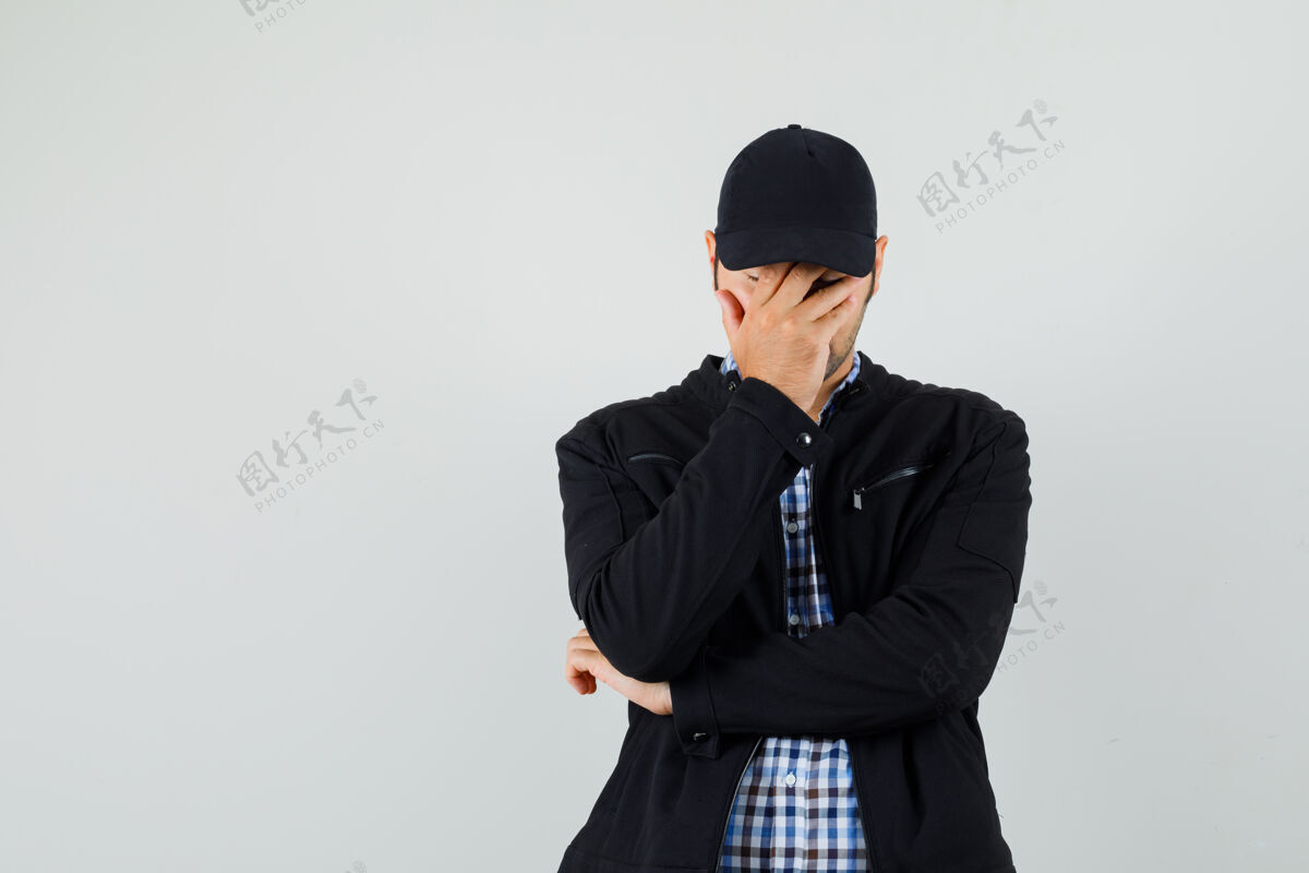 发型一个穿着衬衫 夹克 帽子的年轻人 手放在脸上 看起来很沮丧沮丧自信衬衫