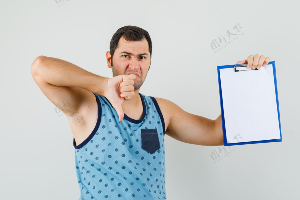 朋友年轻人拿着写字板 在蓝色的单打中竖起大拇指 看起来很不满衬衫男性剪贴板