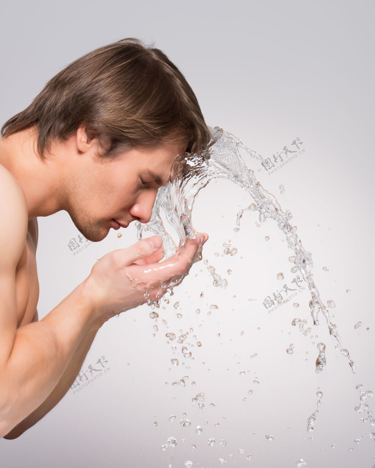 强一个英俊的男人在灰色的墙上用水洗脸的肖像轮廓成人肌肉