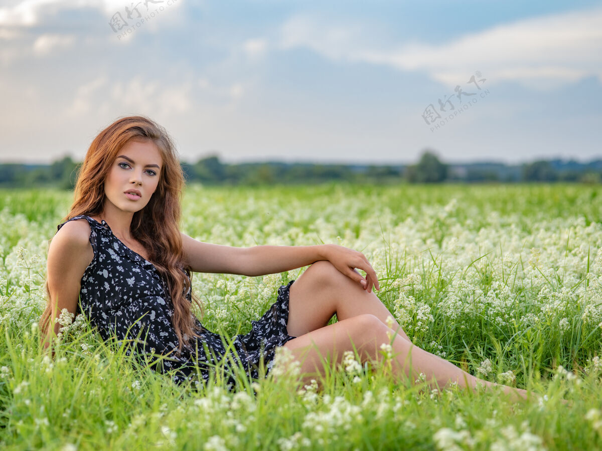 服饰模特在一片白色的薰衣草花丛中摆姿势年轻女子坐在户外一片白色的花丛中放松完整肖像坐着