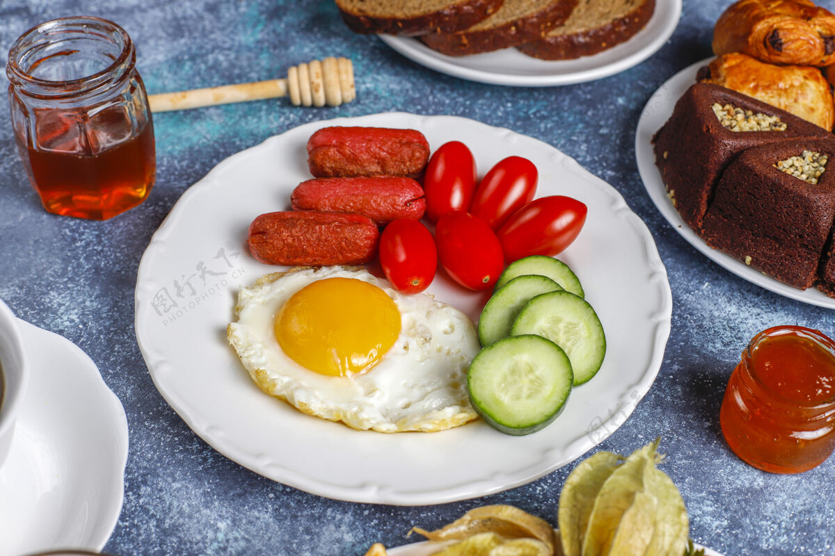 西红柿早餐盘子里有鸡尾酒香肠 煎蛋 樱桃番茄 糖果 水果和一杯桃子汁早餐蛋黄鸡蛋