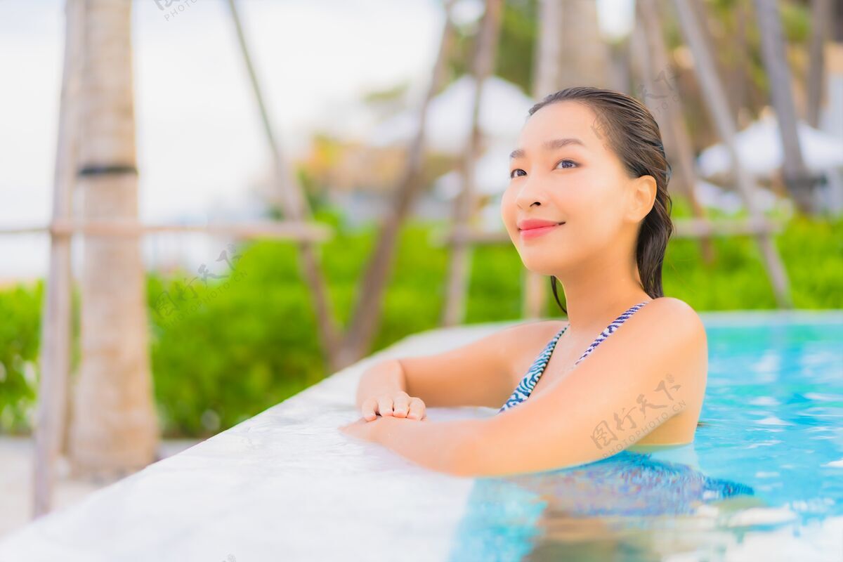 无限肖像美丽的亚洲年轻女子放松休闲周围的室外游泳池与海洋海滩游泳女人游泳