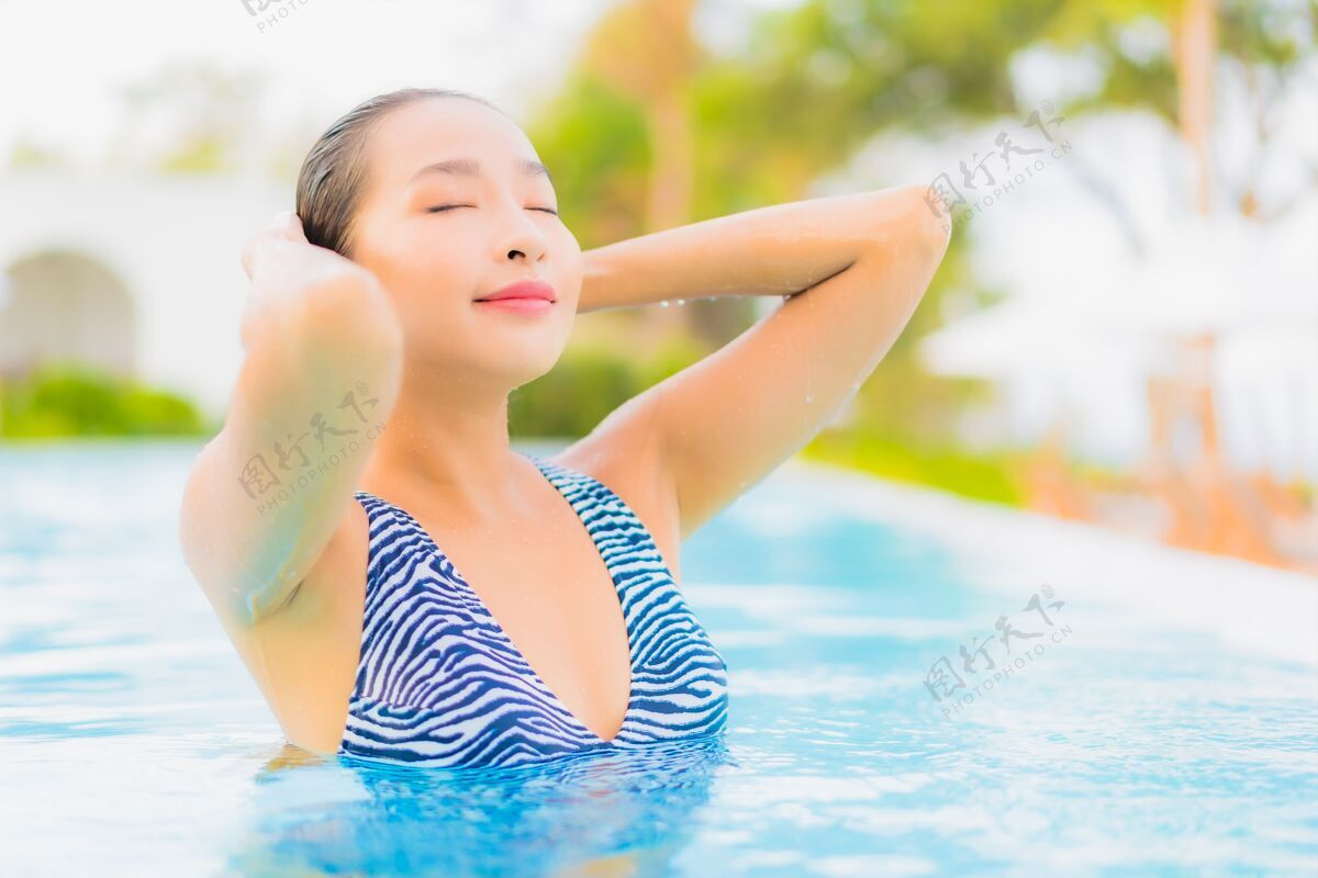 景观肖像美丽的亚洲年轻女子放松休闲周围的室外游泳池与海洋海滩无限度假水