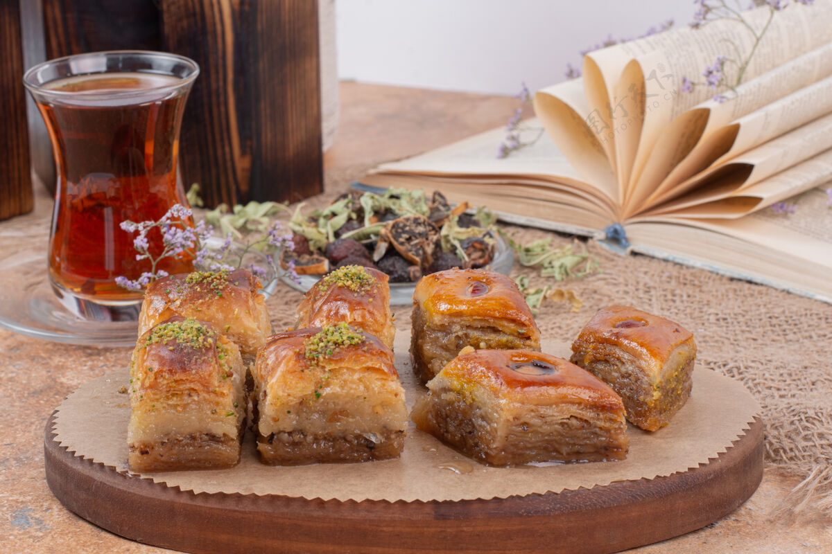 盘子一杯茶和传统的开心果烤熔岩放在大理石桌上木头盘子饮料甜点