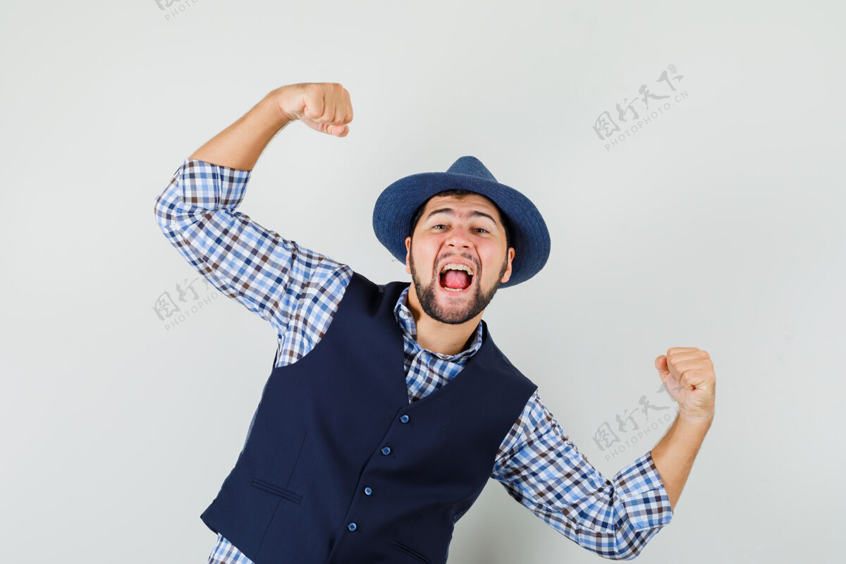 现代穿着衬衫 背心 帽子 看起来很高兴的年轻人展示了赢家的姿态成功衬衫自信
