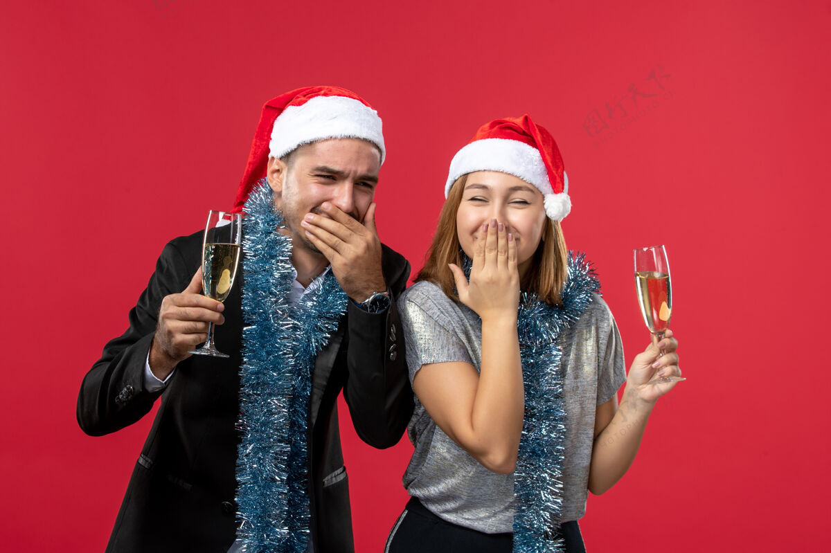 表演正面图红墙上庆祝新年的年轻夫妇爱圣诞派对饮料演员庆典明星