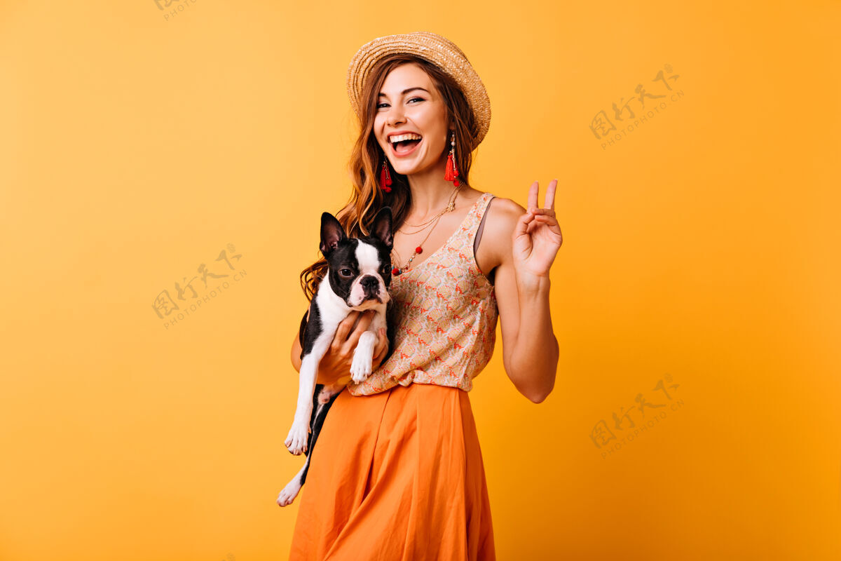 欢乐时尚的女孩抱着法国斗牛犬大笑乐观的红发女士和她的狗在工作室里放松休闲动物橙色