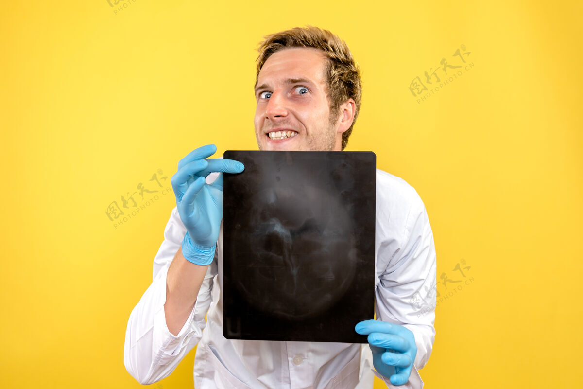 医疗正面图黄色桌子上拿着x光片的男医生医疗外科卫生科维德成人X光Covid