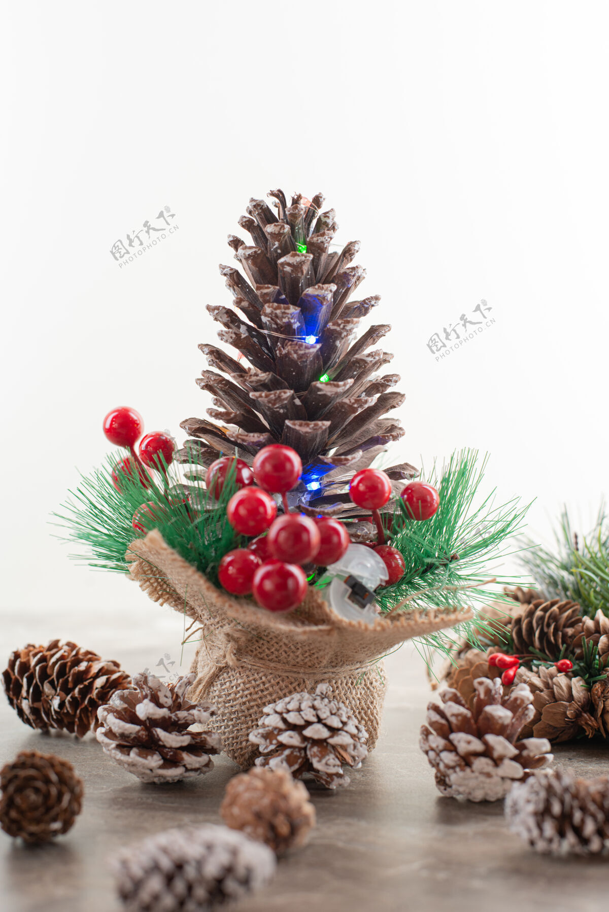 圆锥体木桌上装饰着冬青浆果和灯光的松果装饰十二月圣诞节