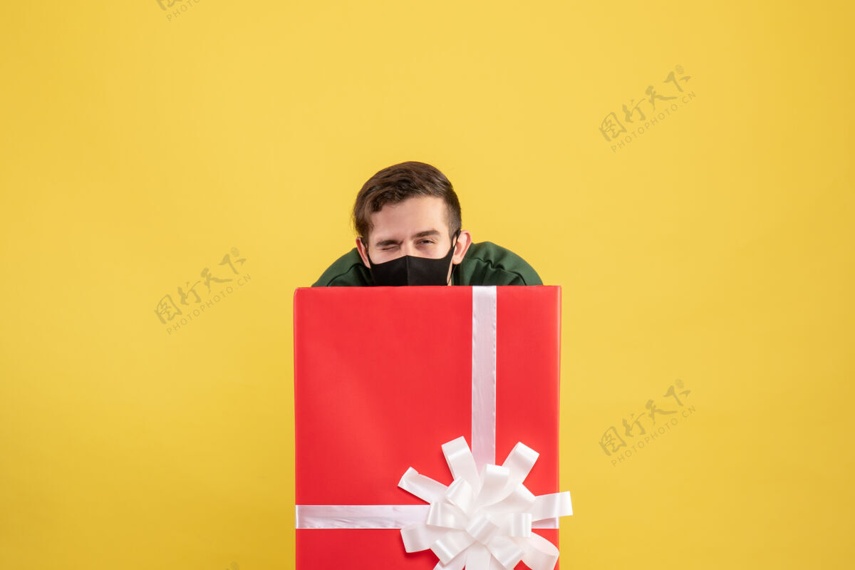 蜡笔正面图：年轻人躲在黄色的大礼品盒后面生日空间庆祝