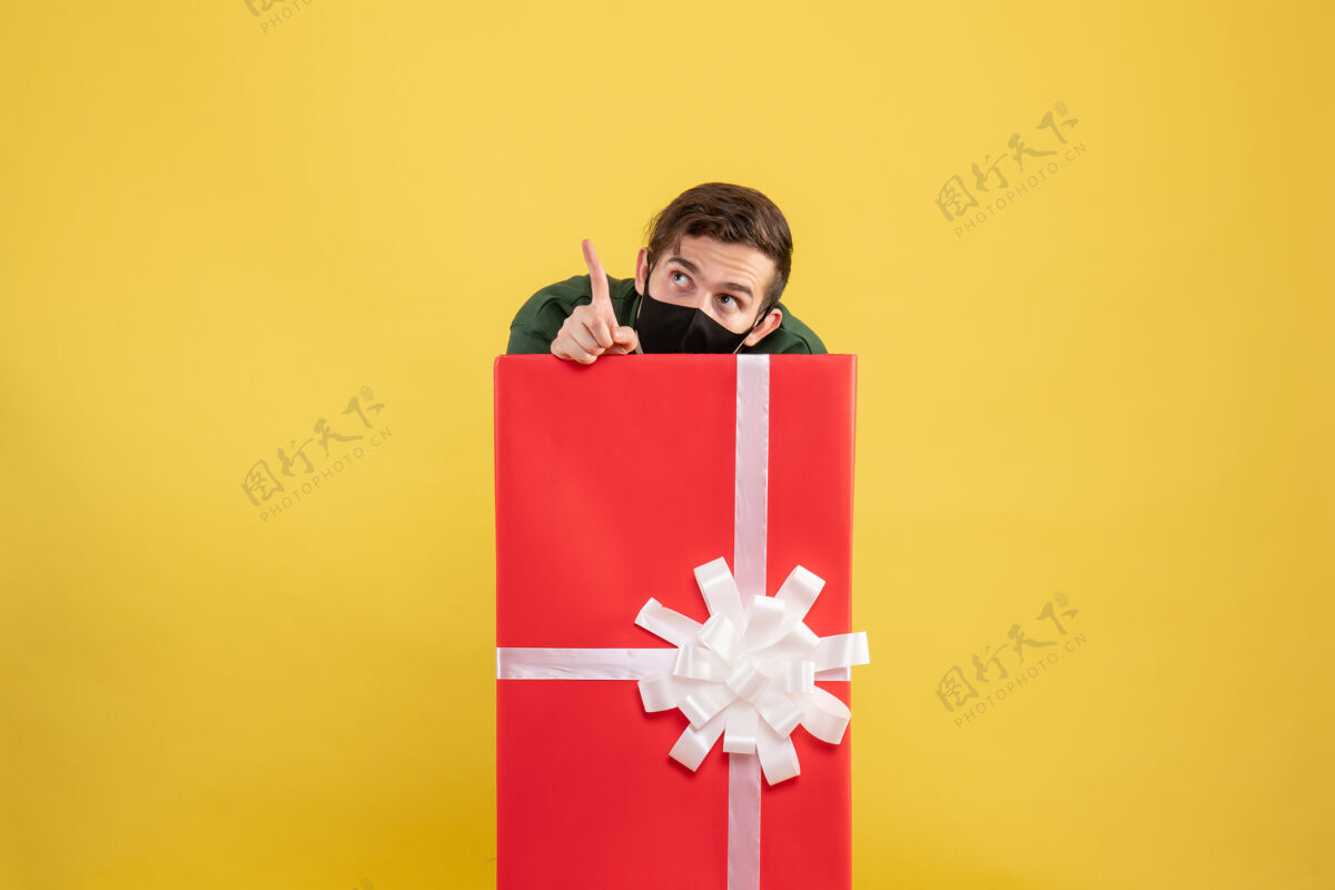 包正面图：年轻人躲在黄色的大礼品盒后面漂亮微笑礼物
