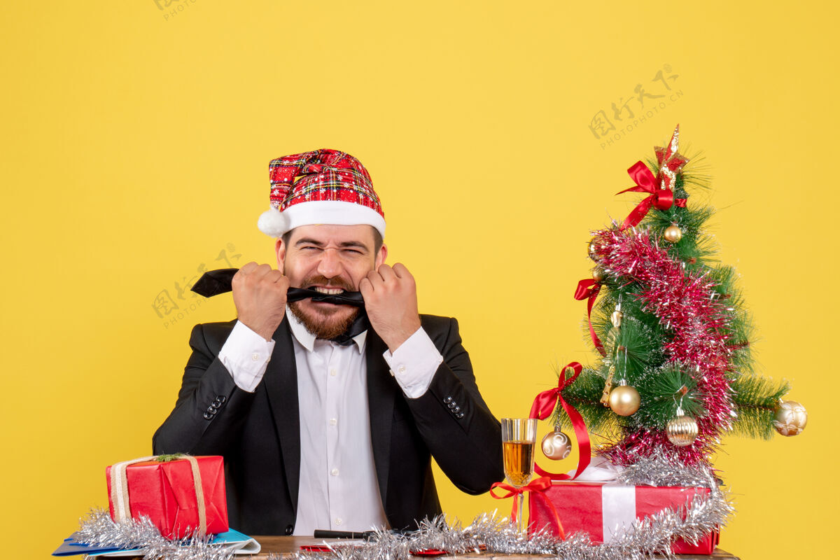 新郎正面图男性工人坐在桌子后面 黄色的桌子上放着礼物工人坐着礼物