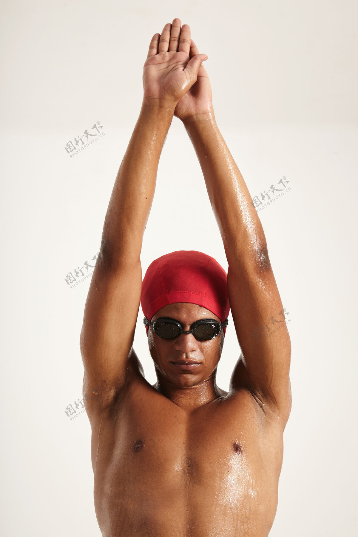 相机一位面容严肃 肌肉发达的年轻美籍非洲裔游泳运动员 头戴红帽子 戴着黑色护目镜 举手跳入白色的水中高活跃运动员