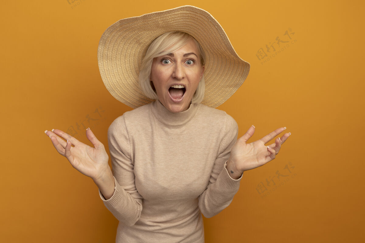 橙色兴奋的金发斯拉夫女人 戴着沙滩帽 双手张开 看起来很孤立高级帽子摆姿势