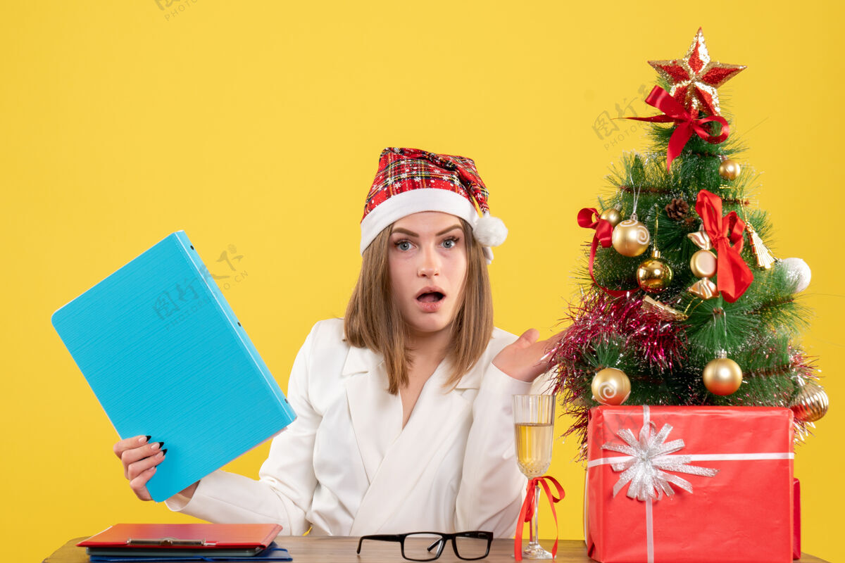 人前视图女医生坐在圣诞礼物持有黄色背景文件情感人女
