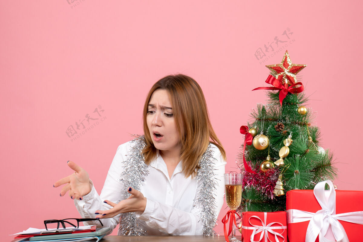 坐着女工围坐在粉色的圣诞礼物旁的正视图人们工人家
