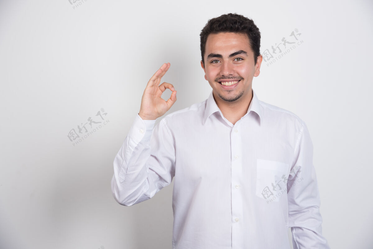 男人年轻的商人用一只手在白色背景上做ok标志积极年轻工作