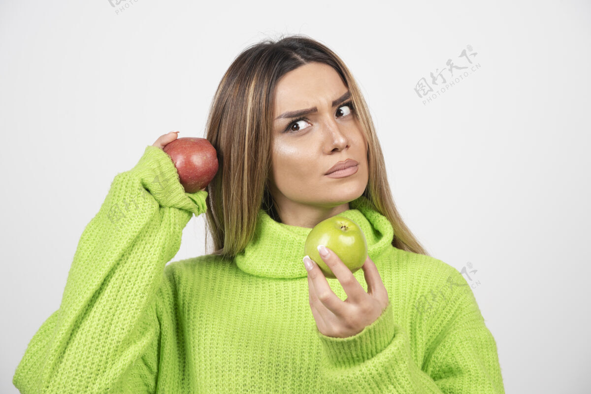保持身穿绿色t恤的年轻女子头顶举着两个苹果女性食欲水果
