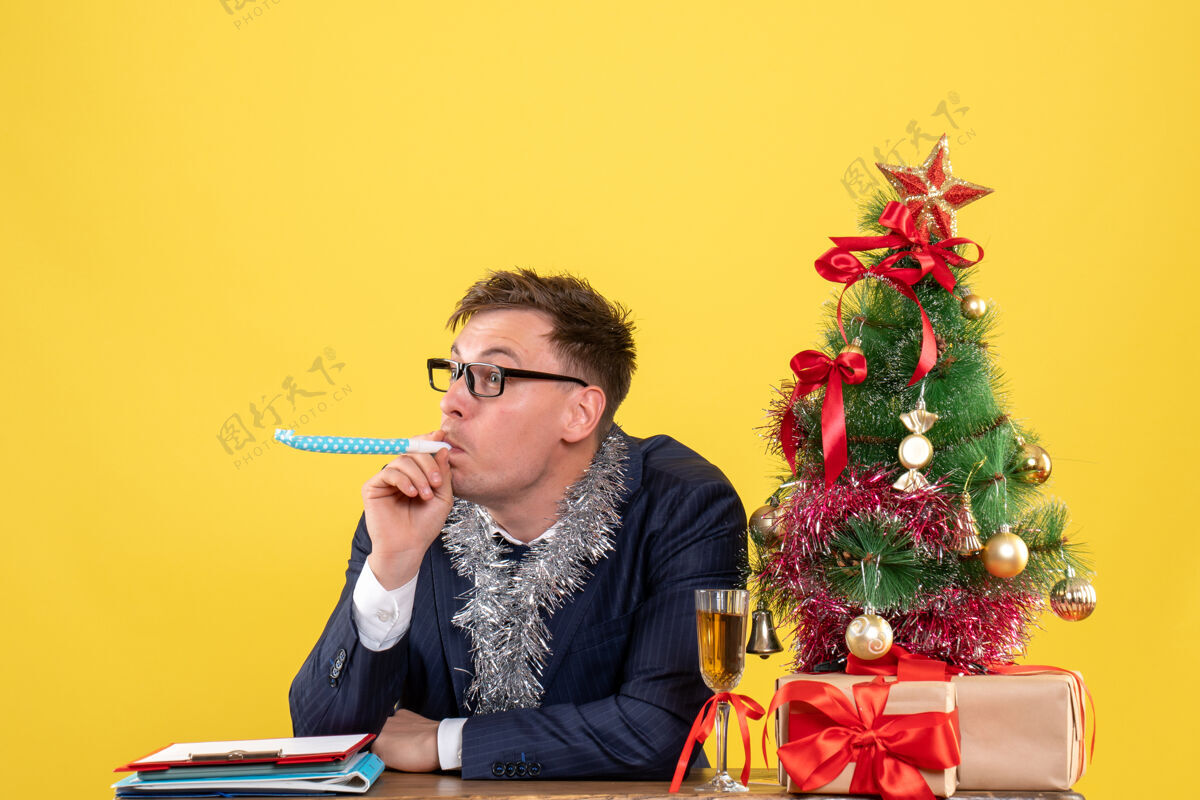 使用戴眼镜的商人在圣诞树附近使用隔音器的前视图 黄色显示表演者人音乐家