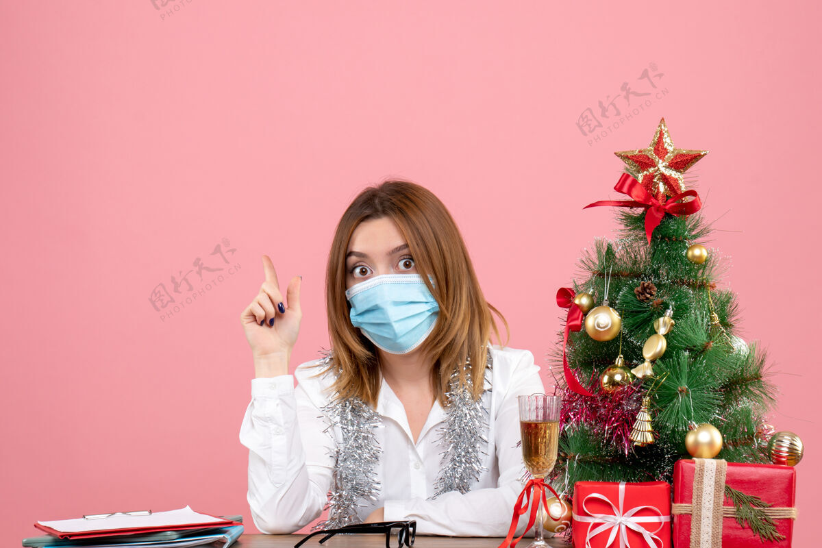 圣诞节女工坐在粉红色的无菌口罩里的正视图女性工作情绪