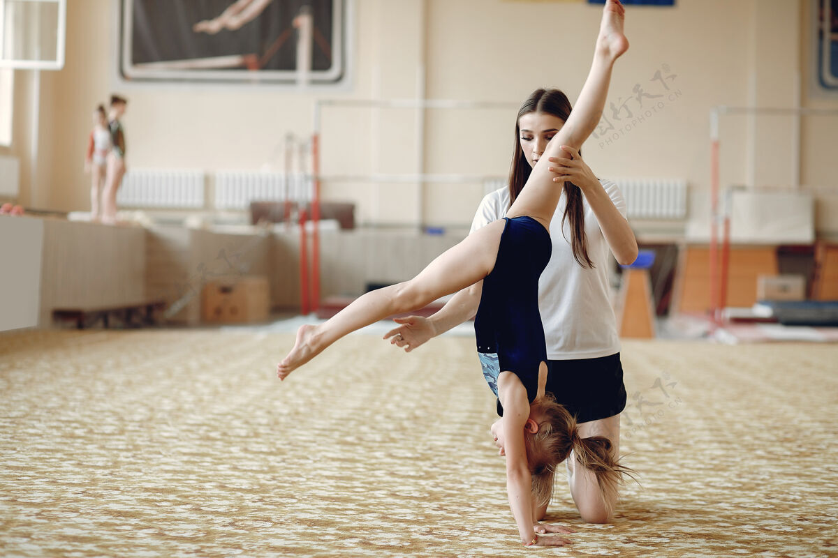 人指导学生女体操运动员 进行各种体操练习和跳跃儿童和体育 健康的生活方式工作室童年灵活